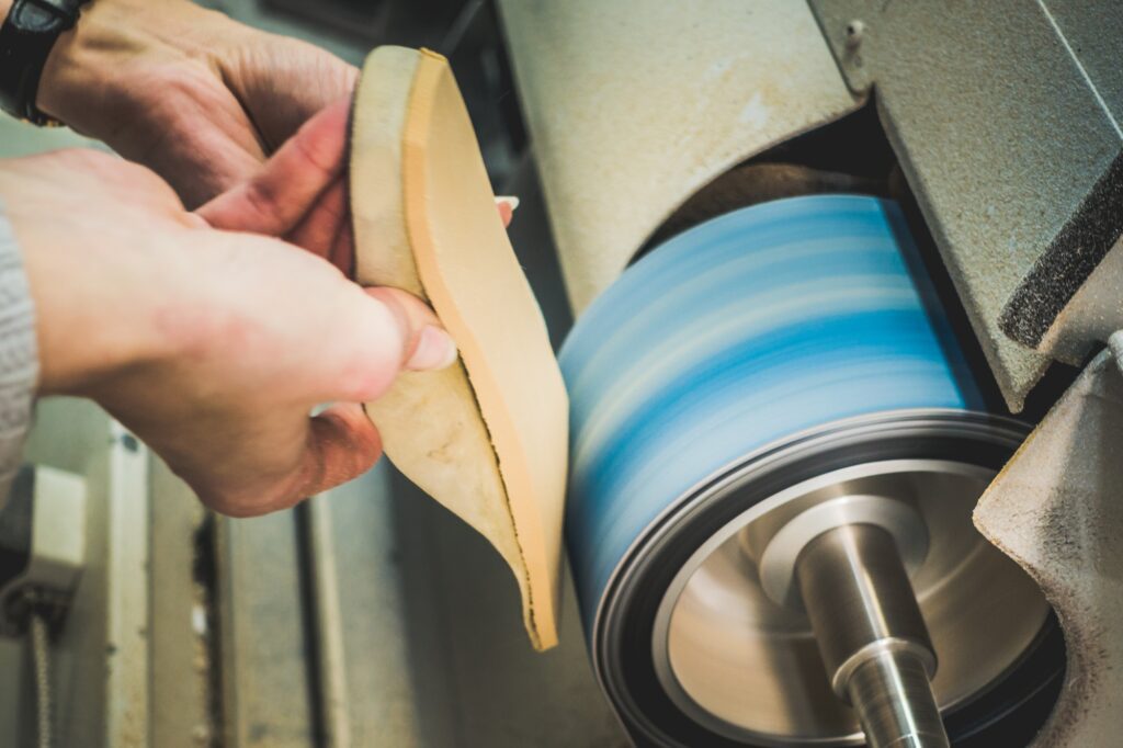 Person shaping a custom orthotic insole using a grinding machine