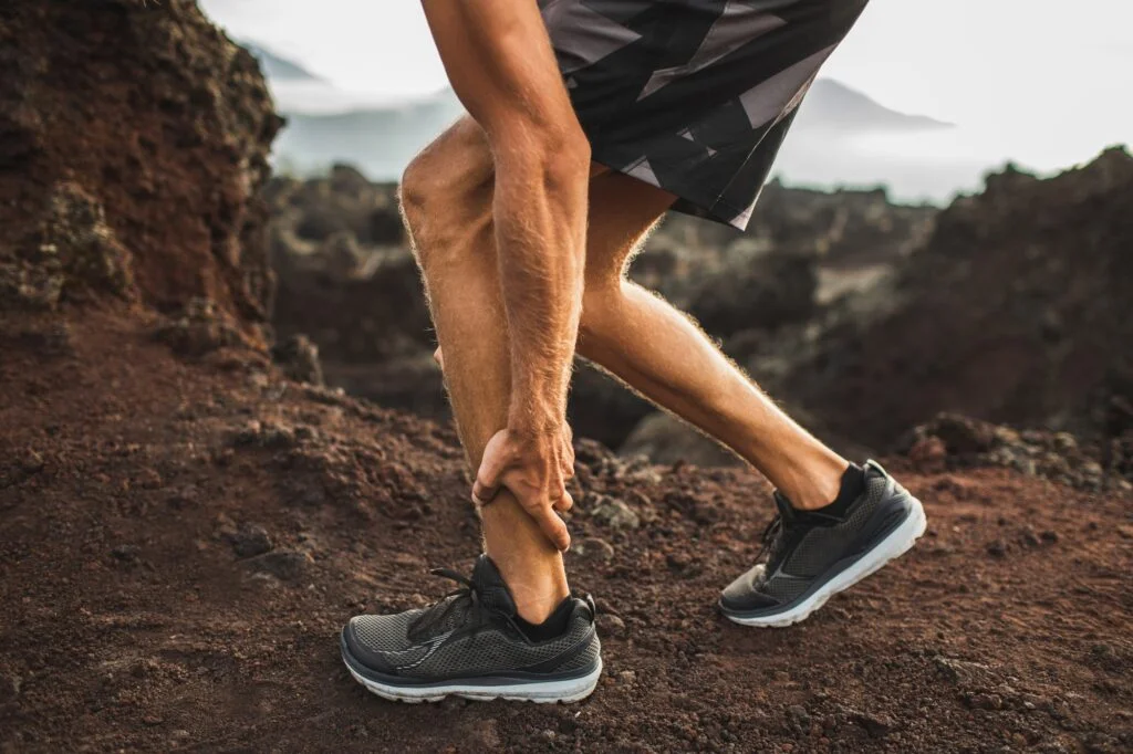 Male runner holding injured calf muscle and suffering with pain