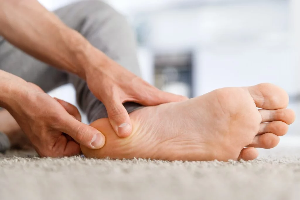 Person pressing their heel due to plantar fasciitis pain